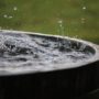4 Tips For Choosing The Best Rainwater Tank For Your Home: Rain Is Falling In A Wooden Barrel Full Of Water In The Garden